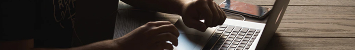 close up of hands hovering above a laptop keyboard