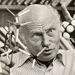 Photograph of Sev Sternhell in his office holding a molecular model and actively explaing some property of the molecule.